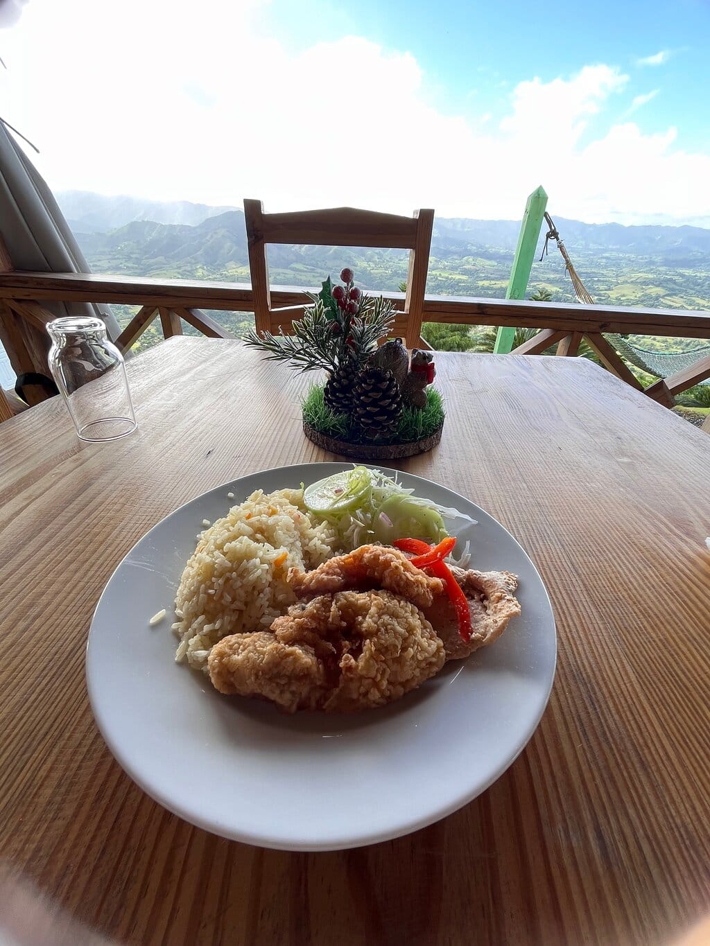 Dominican lunch of rice, fried food, and salad served on a wooden terrace overlooking the mountains